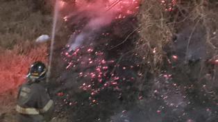 Bombero Zapador trabaja en la extinción de las llamas sobre la barranca de avenida Belgrano.