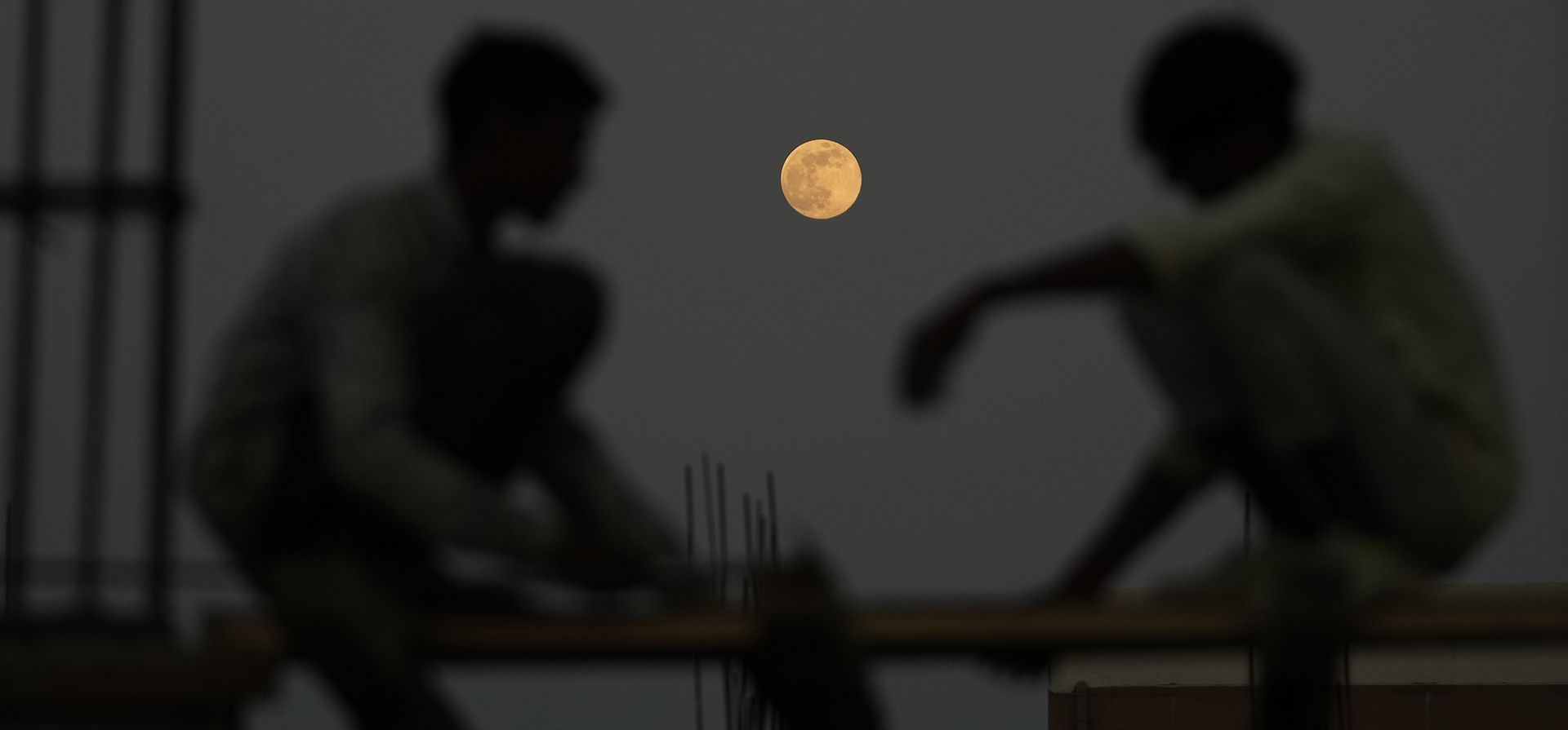 Obreros trabajan en una obra de construcción mientras la superluna se eleva en Ahmedabad, India, el jueves 4 de diciembre de 2025. (Foto AP/Ajit Solanki)