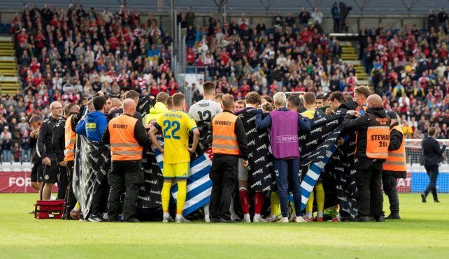 Ambos planteles rodean a Eriksen tras desplomarse en el campo de juego.