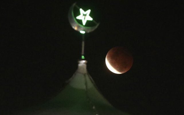 La luna llena se eleva sobre una mezquita mientras se estaba produciendo un eclipse lunar total en Yakarta, Indonesia. El primer eclipse lunar total en más de dos años coincidió con una superluna, creando un fenómeno llamado super "sangre" Luna.