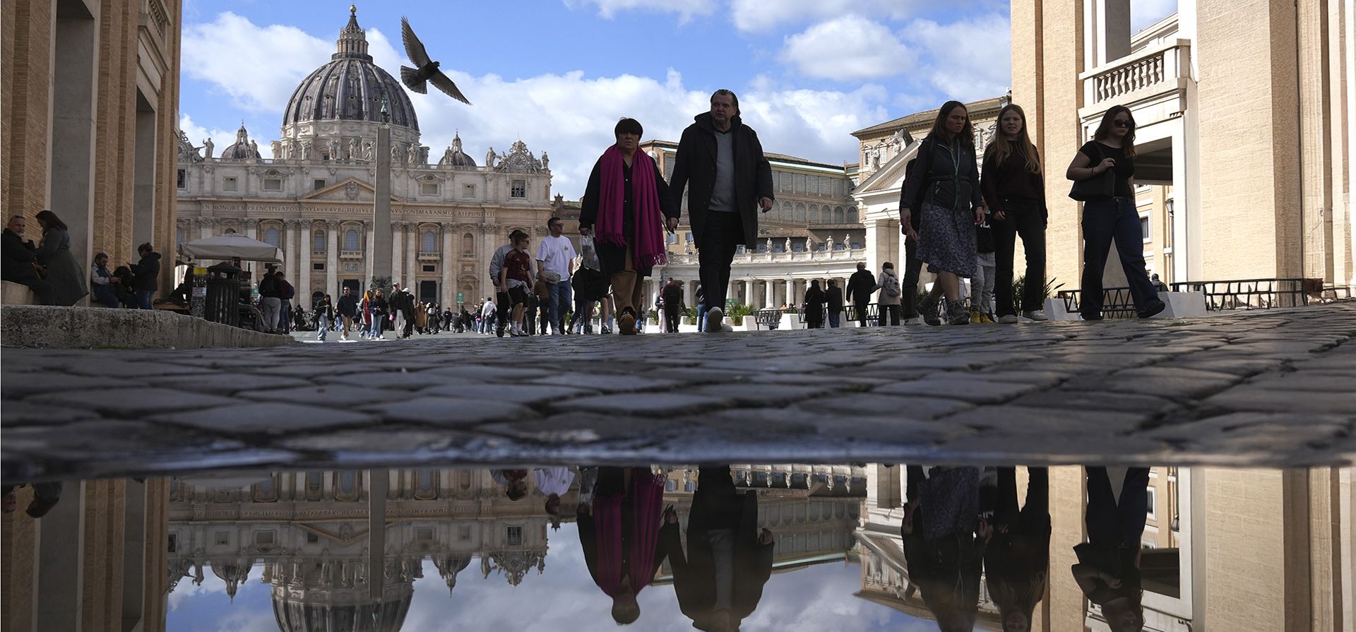 Transeuntes se reflejan en un charco mientras caminan frente a la Plaza de San Pedro en el Vaticano, el jueves 27 de febrero de 2025. (Foto AP/Alessandra Tarantino) Transeuntes se reflejan en un charco mientras caminan frente a la Plaza de San Pedro en el Vaticano, el jueves 27 de febrero de 2025. (Foto AP/Alessandra Tarantino)