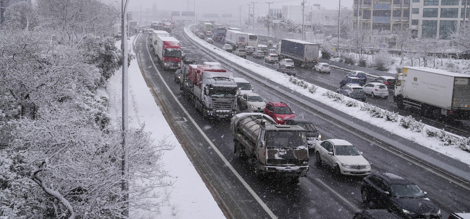 Autos circulan por una carretera alta durante una nevada, al norte de Atenas, el lunes 24 de enero de 2022. Se pronostica que la ola de mal tiempo que azota a Grecia continuará durante la semana.