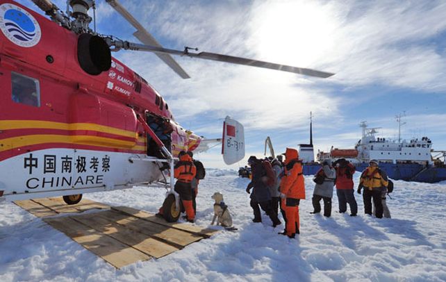 A salvo. Los pasajeros suben al helicóptero. Atrás