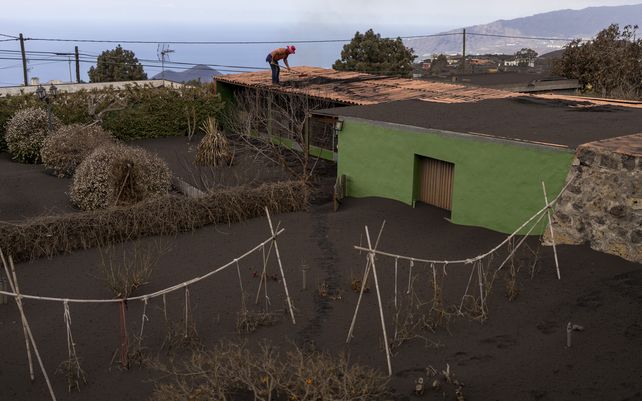 Un hombre quita la ceniza del techo de su casa mientras el volcán continúa en erupción en la isla canaria de La Palma. El volcán continuó emitiendo grandes cantidades de magma