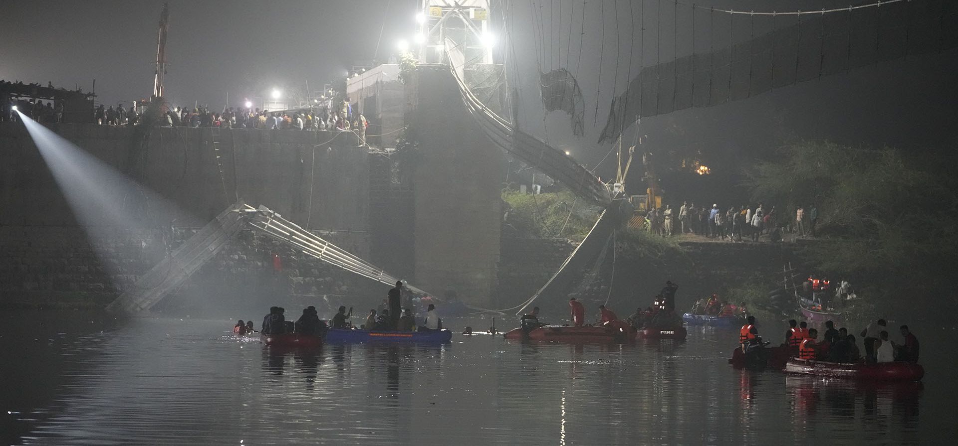 ARCHIVO- Rescatistas en botes buscan en el río Machchu junto a un puente colgante de cable que se derrumbó en la ciudad de Morbi, en el estado occidental de Gujarat, India, el lunes 31 de octubre de 2022. El puente colgante de cable de un siglo de antigüedad se derrumbó en el río el domingo por la noche causando la desaparición de cientos de personas.