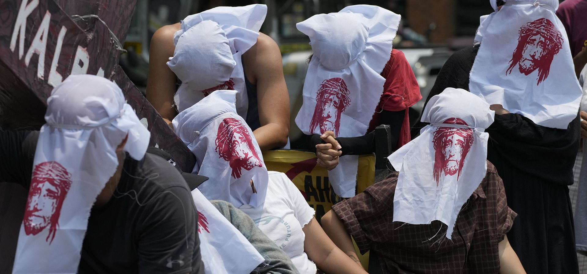 Activistas usan ropa con el rostro de Jesucristo mientras recrean sus sufrimientos durante una protesta de Semana Santa en Manila, Filipinas, el lunes 3 de abril de 2023. El grupo se reunió para crear conciencia sobre las dificultades que sufre la gente cuando comienza la Semana Santa en este país predominantemente romano. nación católica. (Foto AP/Aarón Favila)