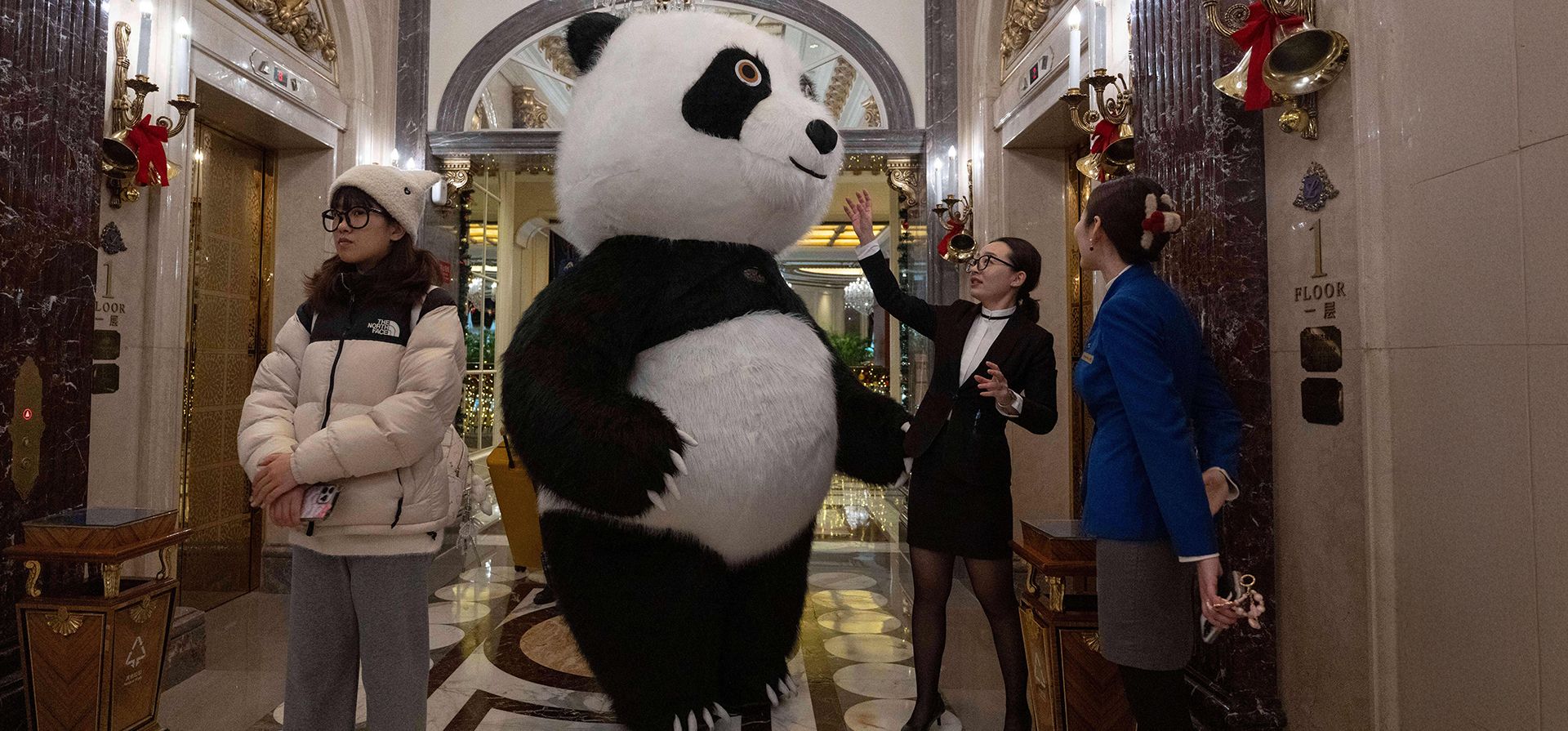 Un miembro del personal del hotel ayuda a un panda mascota a descansar después de entretener a los huéspedes en vísperas de Navidad en Pekín, el miércoles 24 de diciembre de 2025. (Foto AP/Ng Han Guan)