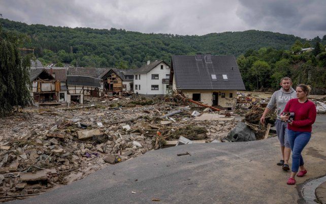 Una pareja pasa junto a casas destruidas en Schuld, Alemania, el jueves 15 de julio de 2021. Debido a las fuertes lluvias, el río Ahr se desbordó dramáticamente la noche anterior.