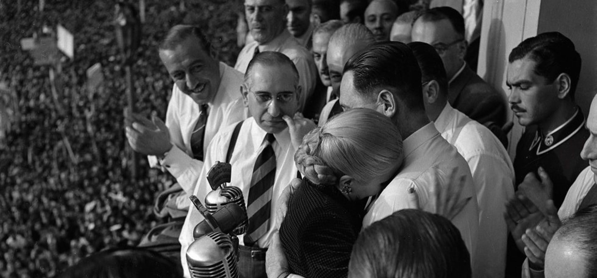 17 de octubre de 1951. Evita acaba de hablar a una multitud congregada en la plaza de Mayo desde el balcón de la Casa Rosada. Se abraza a Perón y llora sobre su pecho. El cáncer avanza sobre ella y debe renunciar a su candidatura a vicepresidenta. El fotógrafo oficial de Perón, Pinélides Aristóbulo Fusco, levanta su cámara sobre la cabeza del funcionario que lo precede y registra la imagen fundacional del mito peronista.