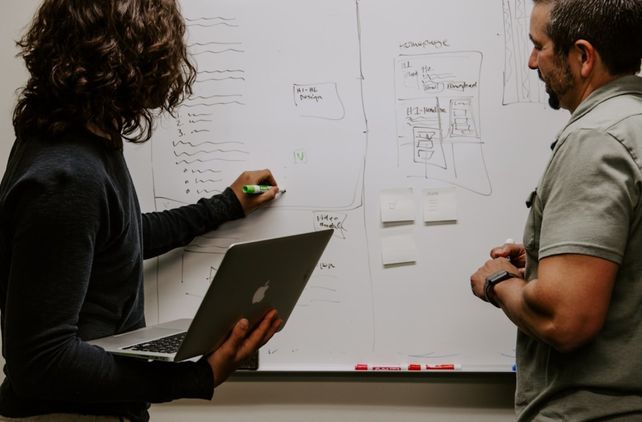 Two men stand by a whiteboard