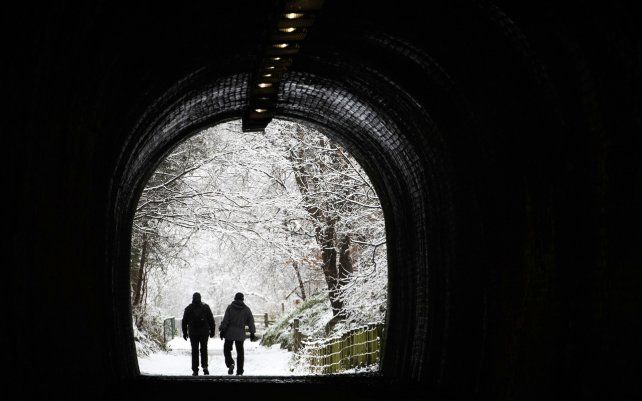 Una pareja camina por un parque nevado en Auchendinny, Escocia.