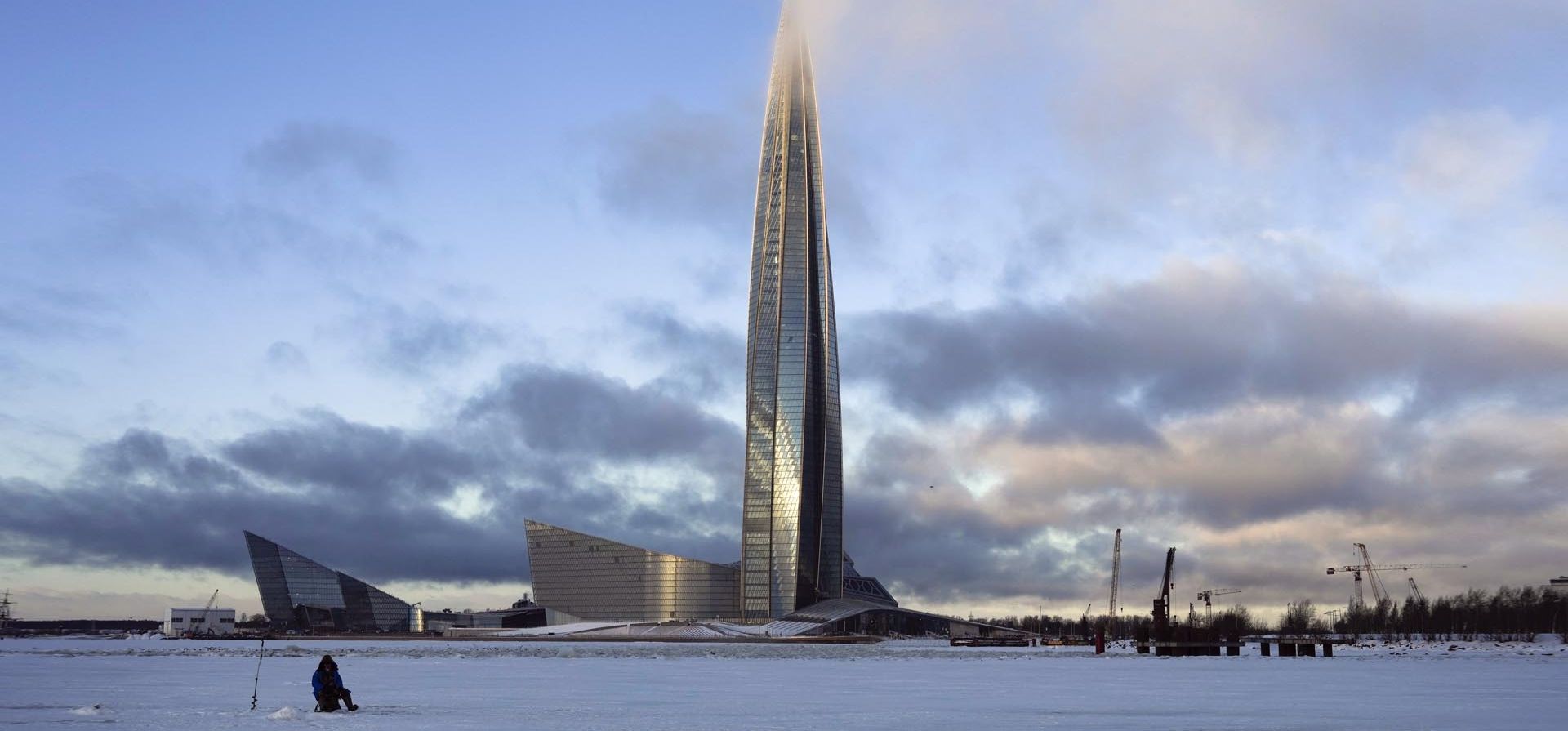 Un hombre pesca en el hielo del golfo de Finlandia junto a la torre comercial Lakhta Center, la sede del monopolio ruso del gas Gazprom cubierto por nubes en San Petersburgo, Rusia. Los gobiernos europeos se esfuerzan por reducir su dependencia energética de Rusia y se preparan para una posible interrupción de los suministros críticos de gas natural a medida que la guerra en Ucrania envía los precios a niveles récord.