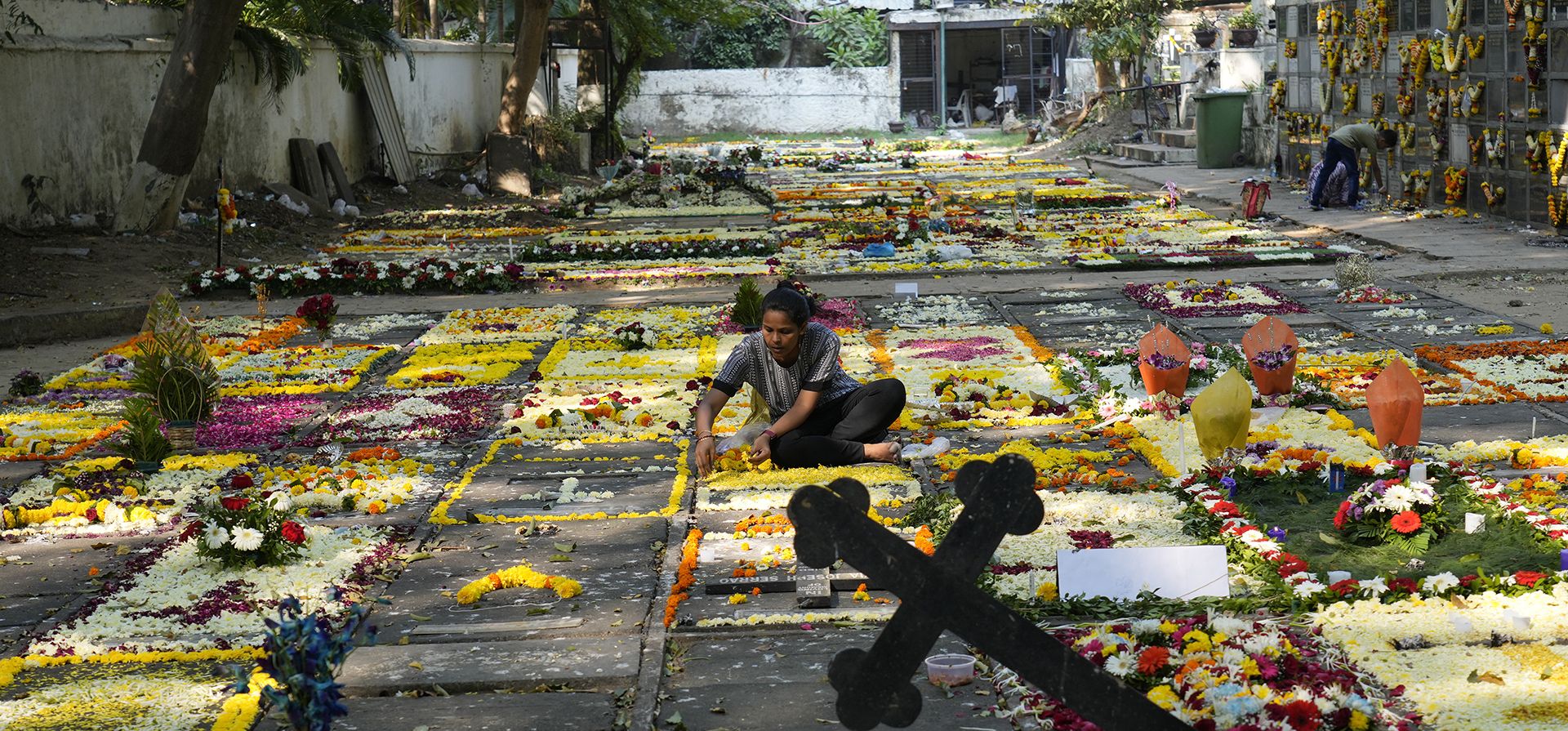 Una mujer arregla flores en una tumba mientras rinde homenaje a las almas difuntas en el Día de Todos los Santos en Mumbai, India, el miércoles 2 de noviembre de 2022.