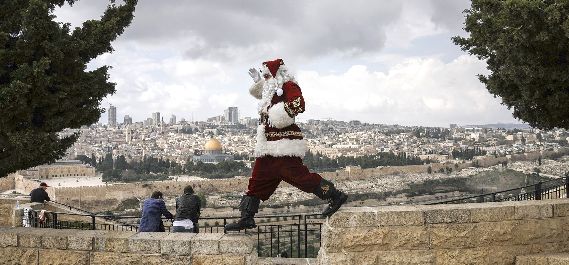 Un hombre vestido como Papá Noel, posa para fotos en el Monte de los Olivos con vista a la Ciudad Vieja de Jerusalén, antes de las próximas vacaciones de Navidad, el martes 6 de diciembre de 2022. Foto: AP/Mahmoud Illean