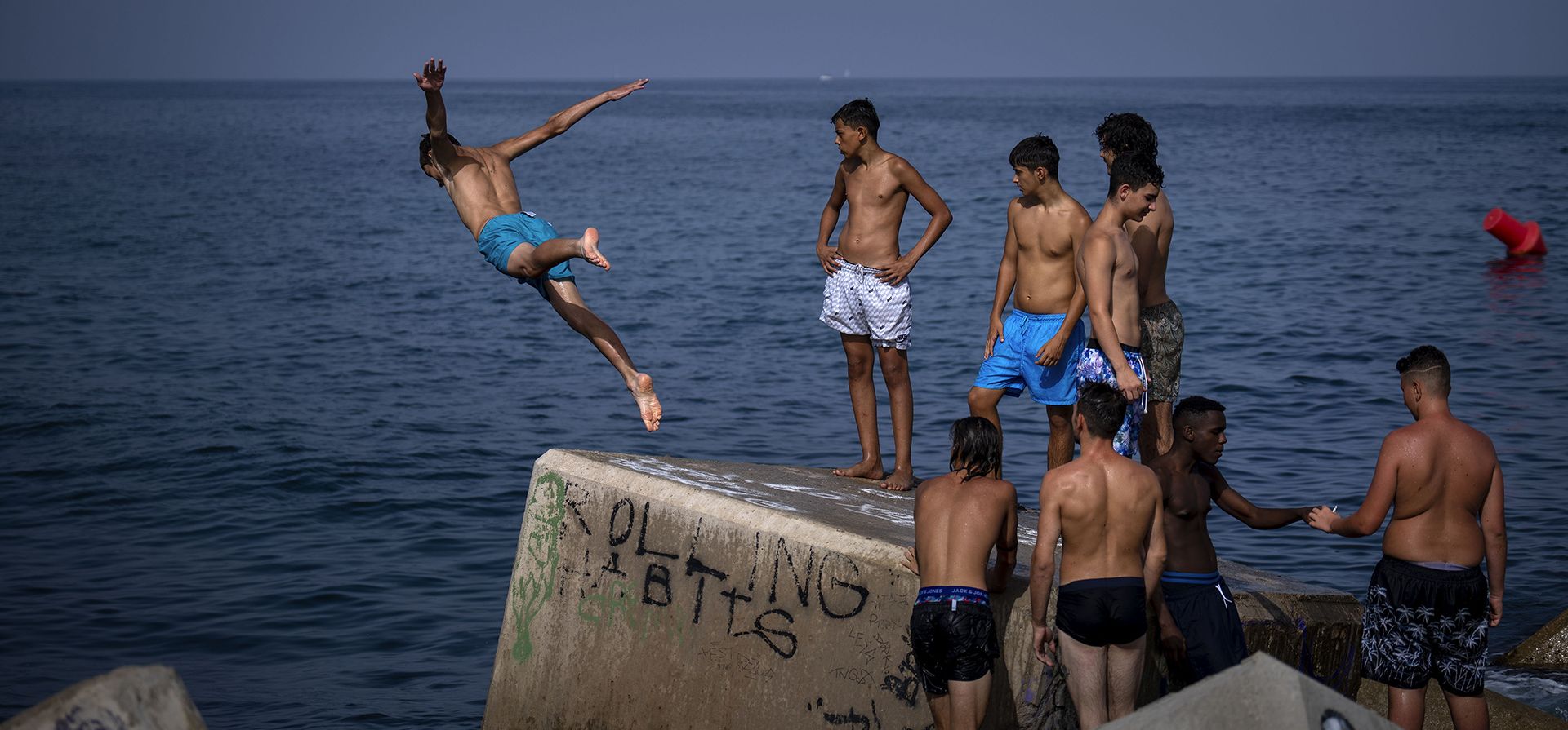 Barcelona, España. Un joven salta al mar para darse un chapuzón. Más de 10 regiones del país ibérico están en alerta roja por el segundo día de una ola de calor sin precedente. Fotografía: Emilio Morenatti/AP Barcelona, España. Un joven salta al mar para darse un chapuzón. Más de 10 regiones del país ibérico están en alerta roja por el segundo día de una ola de calor sin precedente. Fotografía: Emilio Morenatti/AP