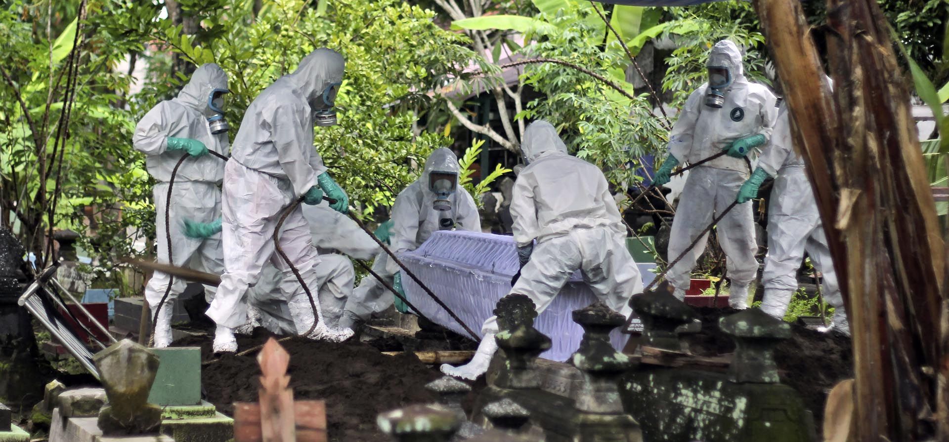 Trabajadores de un cementerio entierran a una víctima de coronavirus durante un funeral en Yogyakarta, Indonesia, el jueves 17 de febrero de 2022.