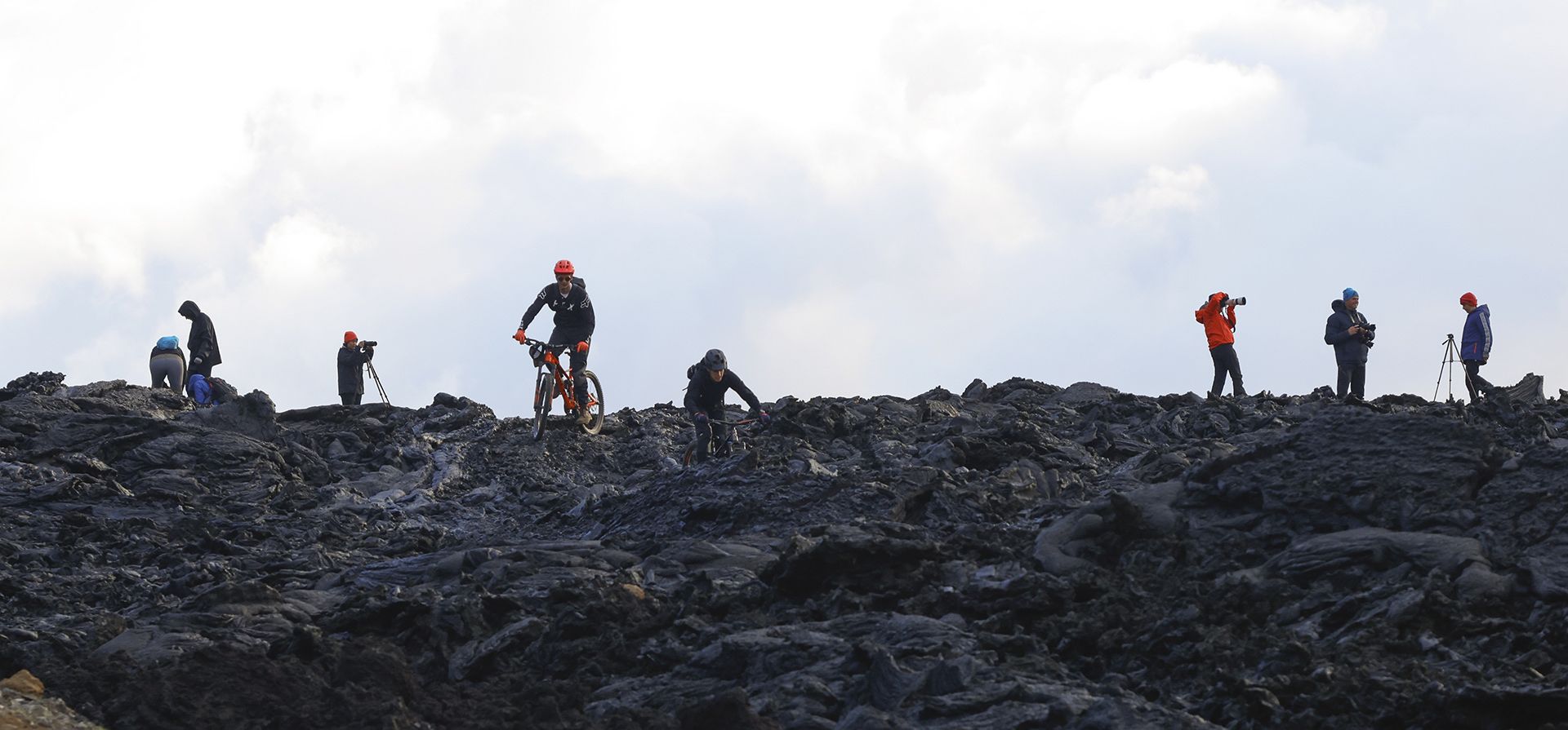 Personas en bicicletas de montaña suben la ladera para tratar de obtener una mejor vista de las erupciones del volcán Fagradalsfjall en Islandia el miércoles 3 de agosto de 2022. Las autoridades del país dicen que el volcán en el suroeste del país está en erupción solo ocho meses después de que terminó oficialmente su última erupción.