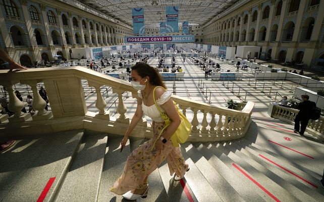 Una mujer sube las escaleras para hacer cola para recibir una vacuna COVID-19 en un centro de vacunación en Gostiny Dvor