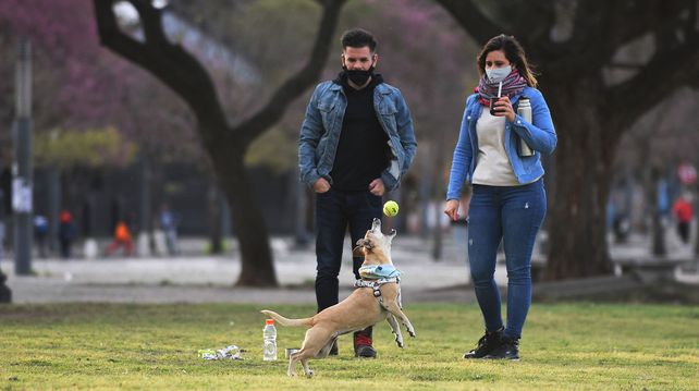 Una pareja juega con su perro en el parque de las Colectividades.