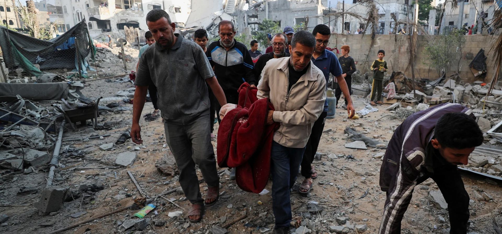 La gente lleva un cuerpo desde el lugar de un ataque israelí contra una casa, Jabaliya, Franja de Gaza. Fotografía: Mahmoud Issa/Reuters La gente lleva un cuerpo desde el lugar de un ataque israelí contra una casa, Jabaliya, Franja de Gaza. Fotografía: Mahmoud Issa/Reuters