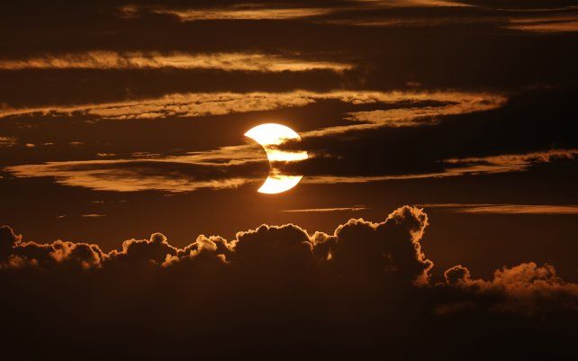Un eclipse solar parcial se eleva detrás de las nubes, en Arbutus, Maryland.