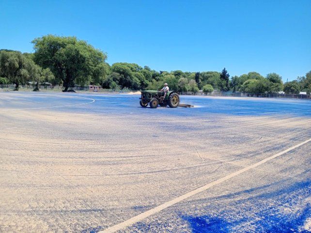 Estudiantes con una nueva cancha de hockey sobre césped. Se terminó con el cepillado para la arena.