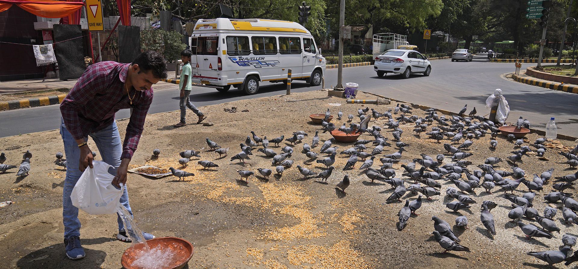 Un hombre llena de agua dulce un recipiente para las aves en un cruce mientras una ola de calor continúa azotando la capital, en Nueva Delhi, India, el lunes 11 de abril de 2022. El martes, el Departamento Meteorológico de India pronosticó que las temperaturas máximas en Nueva Delhi alcanzarían los 41 grados Celsius, casi ocho puntos por encima de lo normal de la temporada.