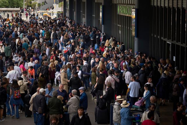 Pasajeros esperan frente a una estaci&oacute;n de trenes cerrada en Barcelona.