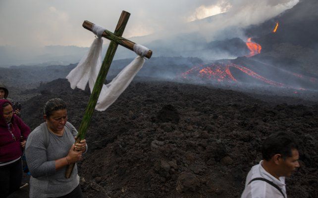 Una mujer lleva una cruz durante una peregrinación para rezar para que el volcán Pacaya disminuya su actividad en San Vicente Pacaya, Guatemala. El volcán ha estado activo desde principios de febrero.