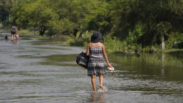 Una mujer camina por el barrio con el agua que le llega a los tobillos.