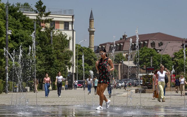 Una joven camina junto a una fuente de la ciudad en Pristina