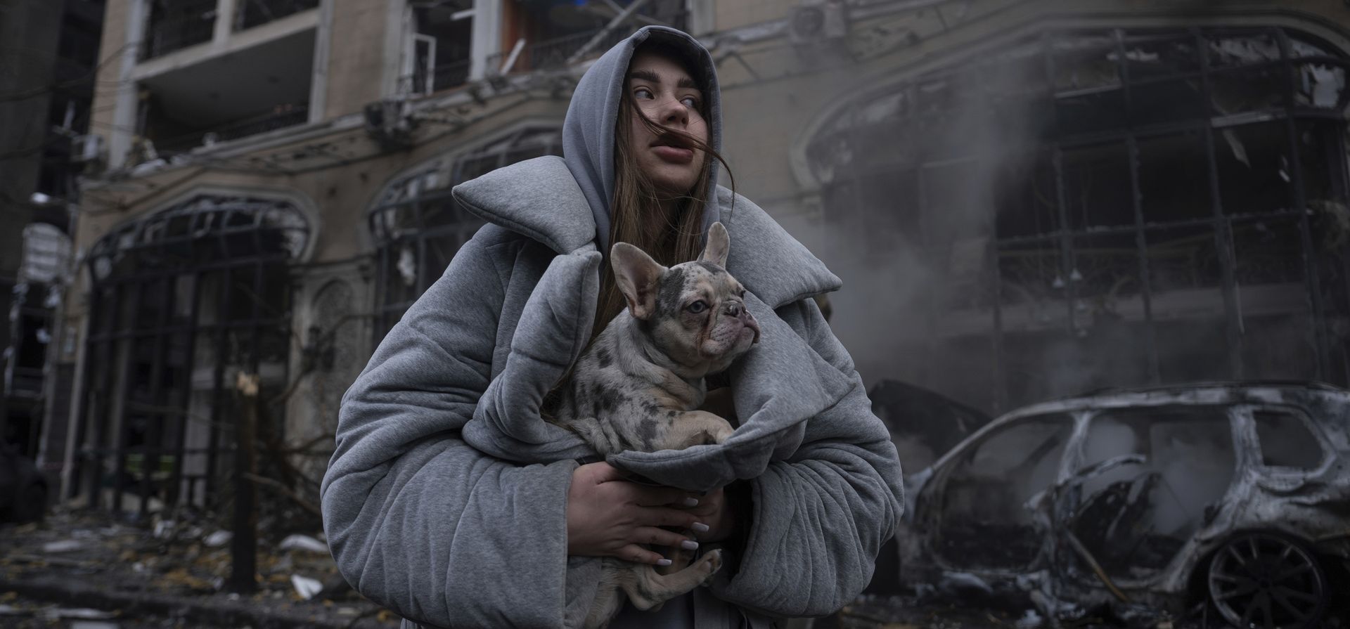 Ivanna calienta a su perro frente a un automóvil destruido en llamas después de un reciente ataque ruso en Kiev, Ucrania, el viernes 20 de diciembre de 2024. (Foto AP/Alex Babenko)