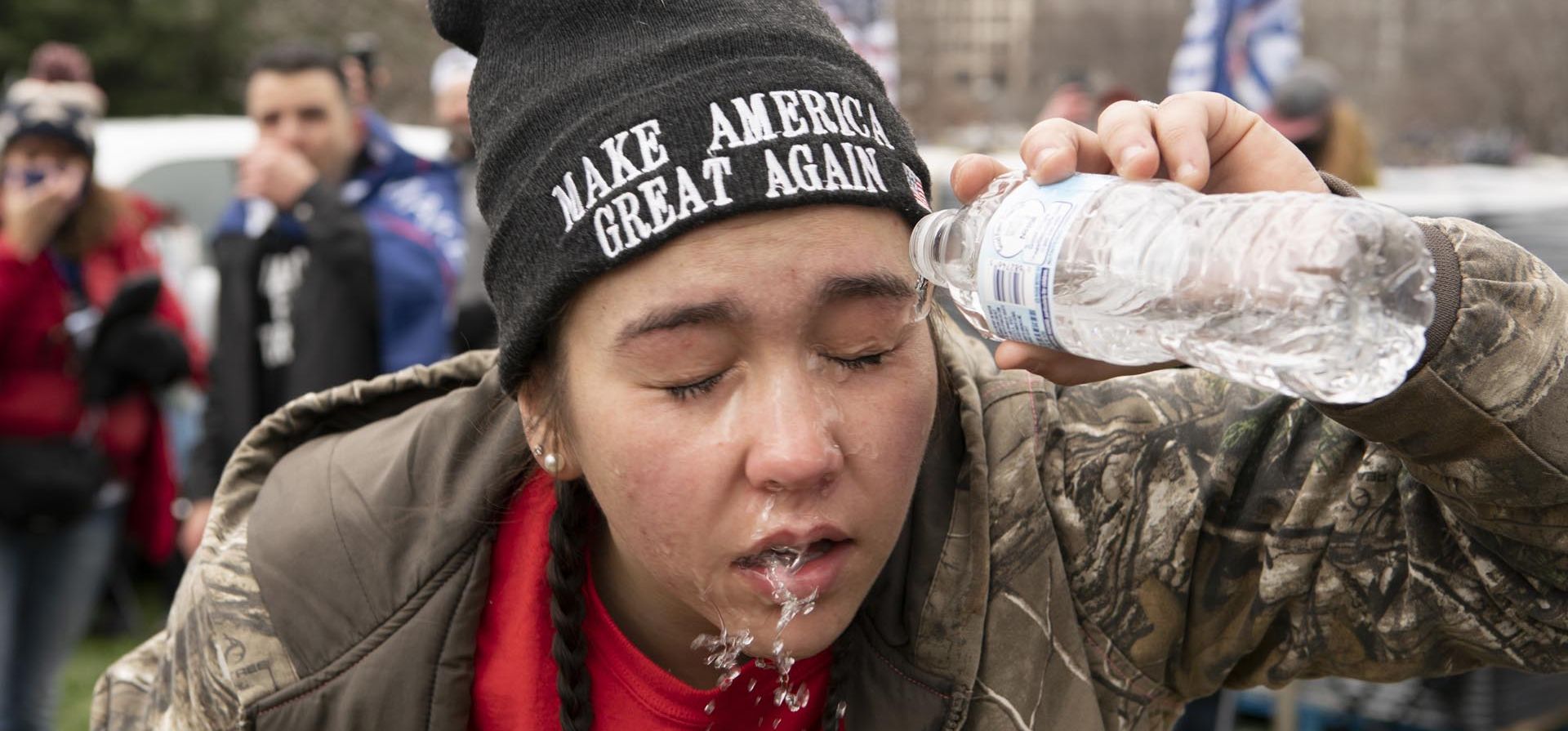 Una manifestante se vierte agua sobre la cara para aliviar el efecto de gases lacrimógenos lanzados por las fuerzas antichoques en el Capitolio de los Estados Unidos el 6 de enero de 2021 en Washington.