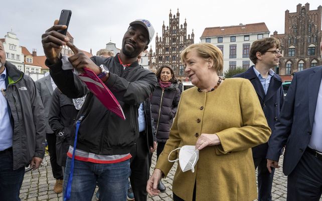 La canciller Angela Merkel, posa para una foto con un visitante en el mercado semanal en su antigua circunscripción en Marlow, Alemania, el jueves 23 de septiembre de 2021.