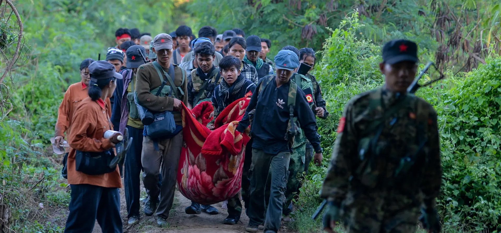 Miembros del Ejército Popular de Liberación cargan a una persona herida, Sagaing, Myanmar. Fotografía: Reuters Miembros del Ejército Popular de Liberación cargan a una persona herida, Sagaing, Myanmar. Fotografía: Reuters