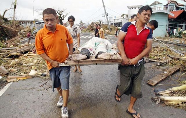 Sobrevivientes transportan a una de las víctimas del “supertifón” de categoría 5 en un sector de la ciudad de Tacloban.