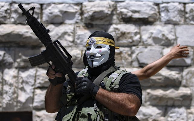 Un manifestante palestino enmascarado dispara al aire después del funeral de Mohammed al-Alami