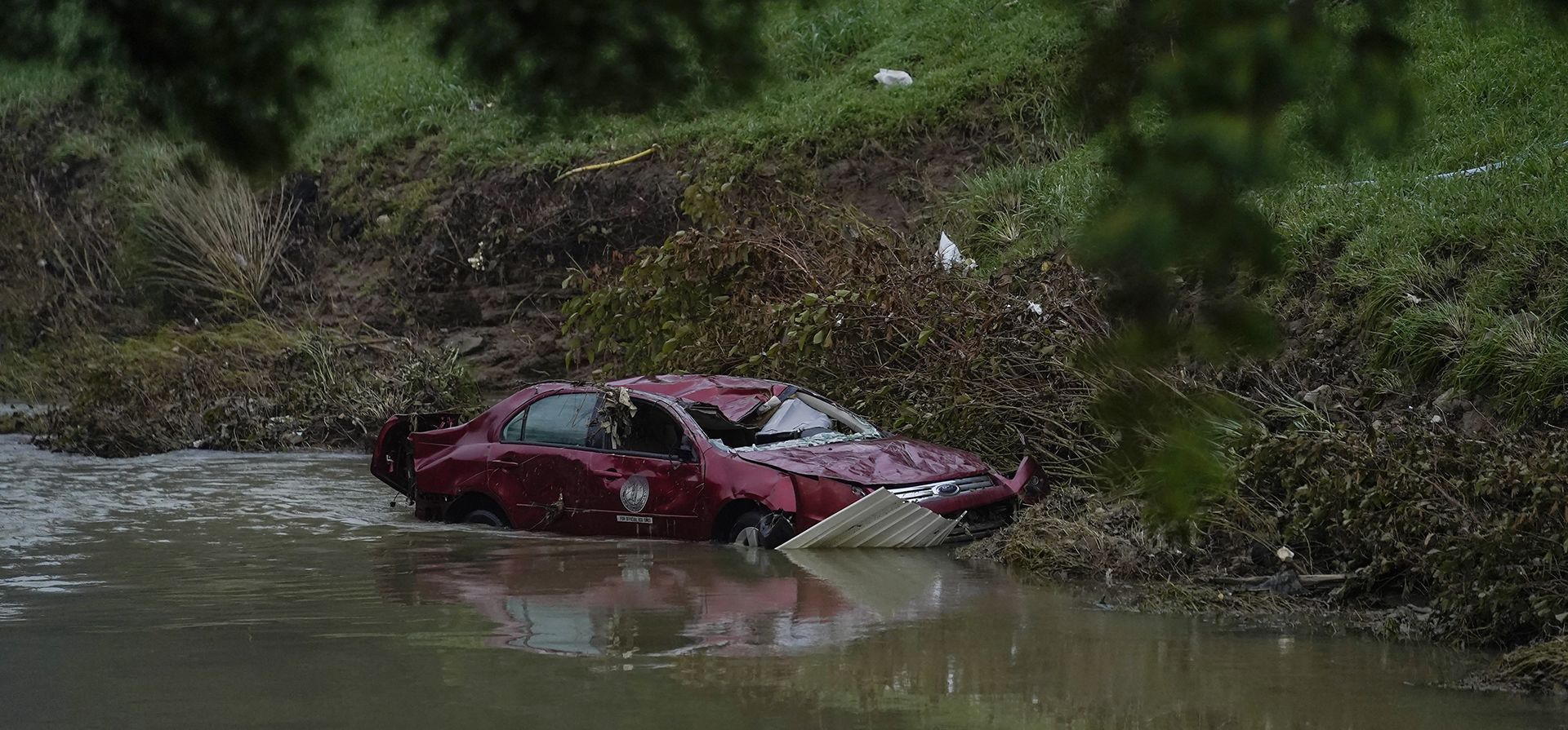 Un automóvil dañado se encuentra en el agua en Hindman, Kentucky., luego de que una inundación masiva llevara el automóvil al agua. Las temperaturas se están disparando en una región del este de Kentucky donde la gente está sacando a pala los restos de las inundaciones masivas.
