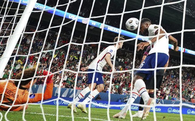 El estadounidense Jordan Siebatcheu Pefok (16) intenta cabecear el balón a la red contra el mexicano Guillermo Ochoa (13) durante el partido de fútbol por el campeonato de la Liga de Naciones de la CONCACAF, el domingo 6 de junio de 2021 en Denver.