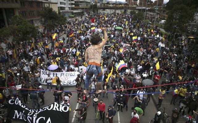 Un artista de cuerda floja hace equilibrio sobre una multitud que marcha durante una protesta contra el gobierno en Bogotá