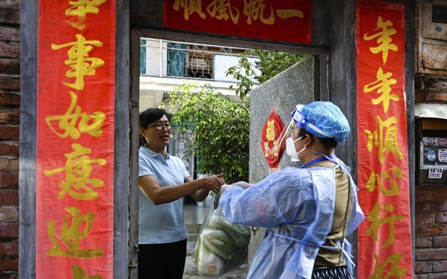 Un trabajador comunitario entrega las necesidades diarias a un hogar bajo administración cerrada en la ciudad de Ruili, en la provincia de Yunnan, suroeste de China, obligando a residentes a quedarse en casa a medida que se expandía un nuevo brote de COVID-19.