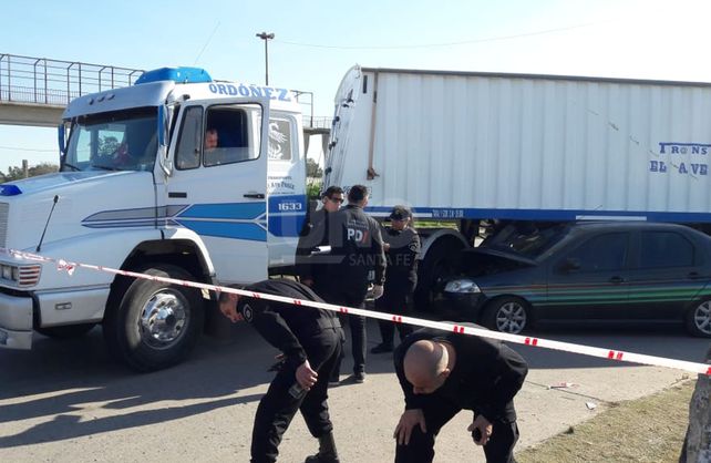 El auto oficial quedó bajo una camión.