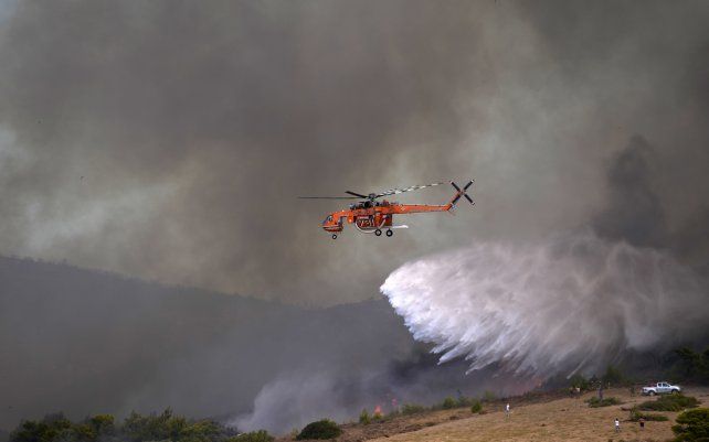 Un helicóptero arroja agua sobre un incendio en el pueblo de Siderina a unos 55 kilómetros al sur de Atenas, Grecia. Las autoridades griegas han desplegado un gran operativo para controlar un incendio forestal que se desató este lunes.