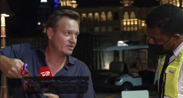 El periodista danés le muestra una acreditación a un agente de seguridad que le impedía hacer su trabajo. (Imagen de video)