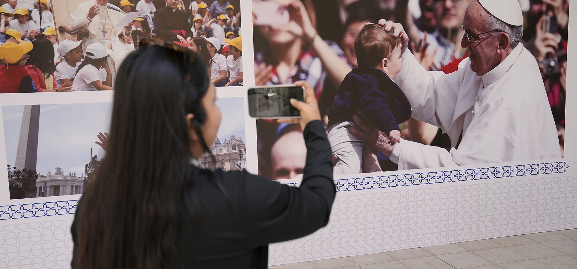 Una mujer toma fotografías con su teléfono móvil a los carteles del Papa Francisco, afuera de la iglesia del Sagrado Corazón, en Manama, Bahréin, el miércoles 2 de noviembre de 2022. El Papa Francisco realizará la visita del 3 al 6 de noviembre para participar en una reunión patrocinada por el gobierno.