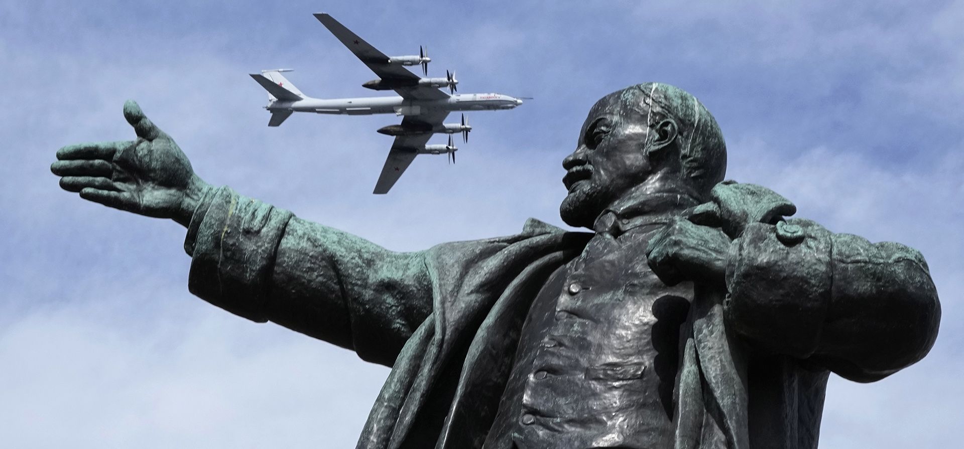 Un Tupolev Tu-142MK, avión ruso de reconocimiento marítimo y guerra antisubmarina, vuela sobre una estatua del fundador de la Unión Soviética, Vladimir Lenin, durante un ensayo del desfile naval en San Petersburgo, Rusia, el jueves 28 de julio de 2022.