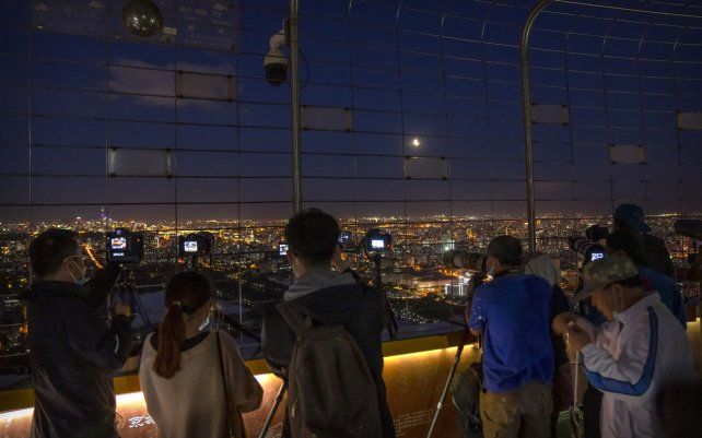Fotógrafos de distintos medios toman fotos de un eclipse lunar en la Torre Central de Televisión de Beijing. El primer eclipse lunar total en más de dos años coincide con una superluna de esta semana para un gran espectáculo cósmico.