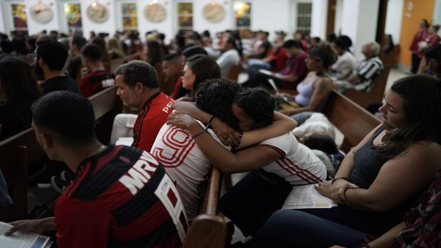 Duelo. Abrazos y llanto durante una misa en memoria de los chicos fallecidos entre las llamas.