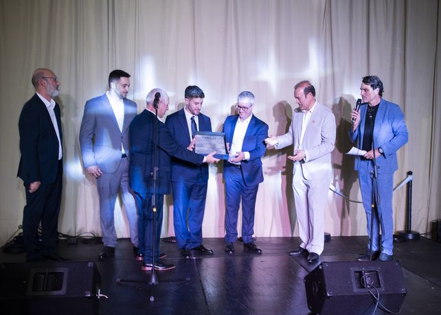 Pablo Javkin entrega una estatuilla de Manuel Belgrano a la familia Picone en la apertura de su nuevo concesionario en la ciudad.