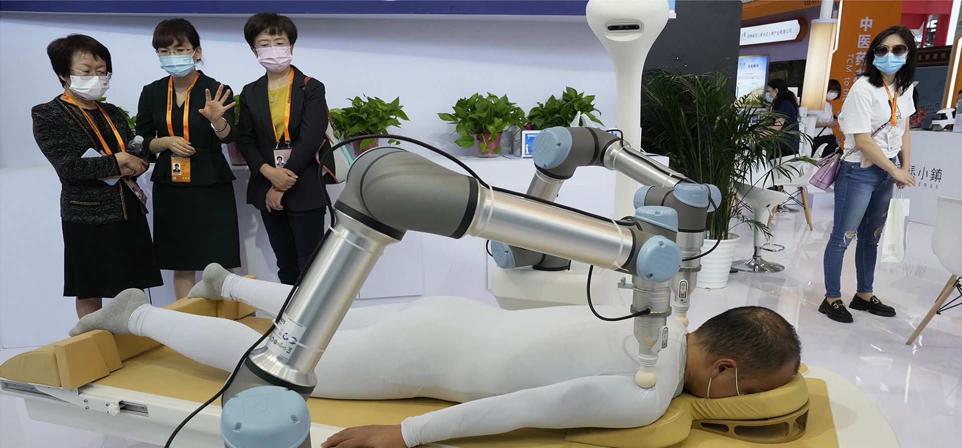 Visitantes observan brazos robóticos realizando masajes de acupresión en un stand durante la Feria Internacional de Comercio de Servicios de China (CIFTIS) en Beijing, el viernes 2 de septiembre de 2022.
